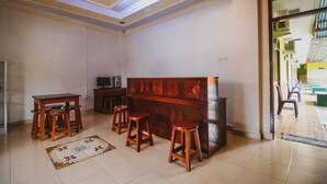 Una habitación con un banco de madera, dos taburetes, una mesita y un televisor.