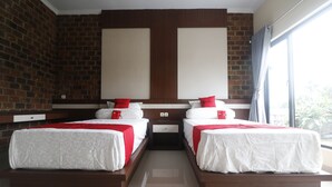 Ein Hotelzimmer mit zwei Betten, einer Ziegelwand und einem großen Fenster.