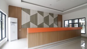Ein Empfangsbereich mit Holztresen, einer Wand mit Muster und einem Fenster mit Blick nach draußen.