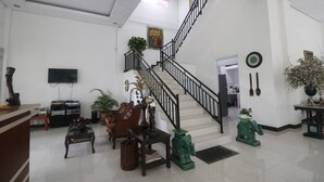 A spacious living area with a staircase, a television, and various furniture including a sofa and chairs.