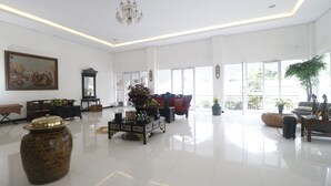 A spacious lobby with a large vase, a chandelier, and a painting on the wall.
