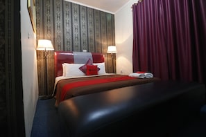 A hotel room with a large bed, two bedside lamps, a red headboard, and a red curtain. - RedDoorz Plus @ Jalan Raden Intan Lampung (Bandar Lampung)