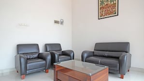 Een kamer met twee leren fauteuils, een leren bank en een salontafel met glazen blad.