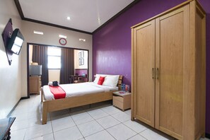 Una habitació d'hotel amb un llit, un armari, un escriptori i una televisió.
