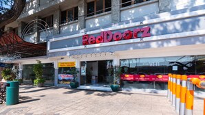 A RedDoorz store with a tiled entrance, potted plants, and a clear sky. - RedDoorz @ Urip Sumoharjo (Surabaya)
