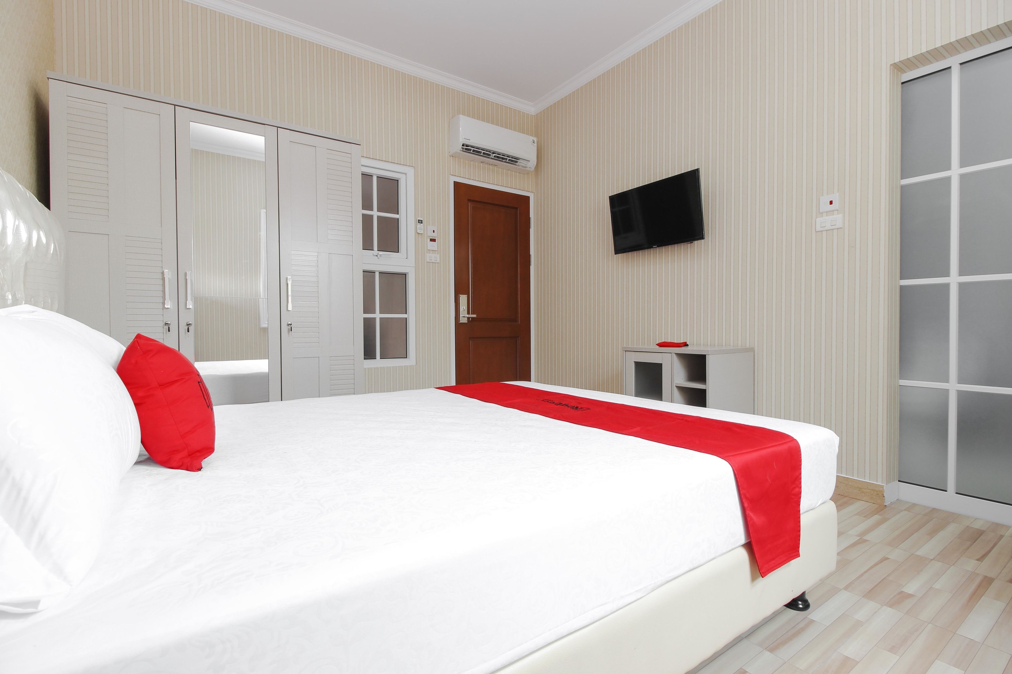 A hotel room with a bed, wardrobe, TV, and a small table.