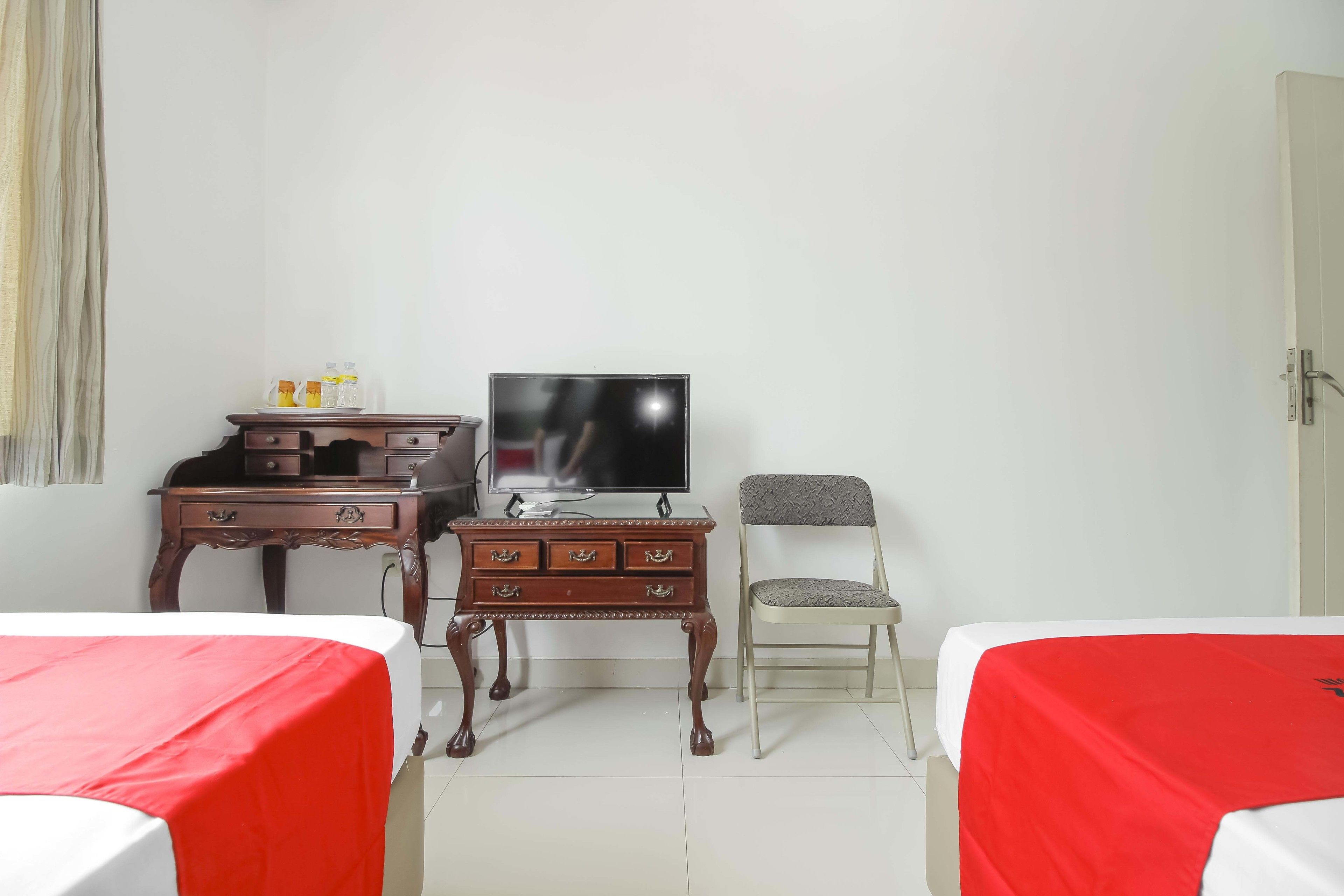 A hotel room with a bed, a TV, a wooden dresser, and a chair.