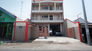 A multi-story building with a gated entrance, a balcony on the upper floor, and a signboard on the left. - RedDoorz @ Sedati (Sidoarjo)