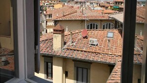 Vista desde una ventana sobre una zona urbana densamente poblada con tejados de tejas rojas y una mezcla de edificios residenciales.