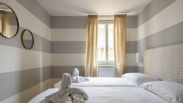 Habitación de hotel con dos camas, un espejo grande y una ventana con cortinas.