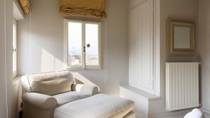 Un dormitorio con cama, ventana, radiador y un espejo en la pared.