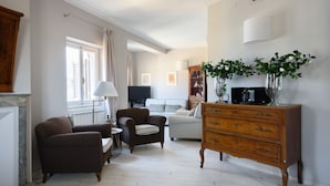 Una sala de estar con chimenea, un sofá, un sillón, un aparador de madera y un televisor.