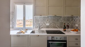 Una cocina moderna con un ventanal grande, un lavamanos, una estufa y un bol de fruta en la encimera.