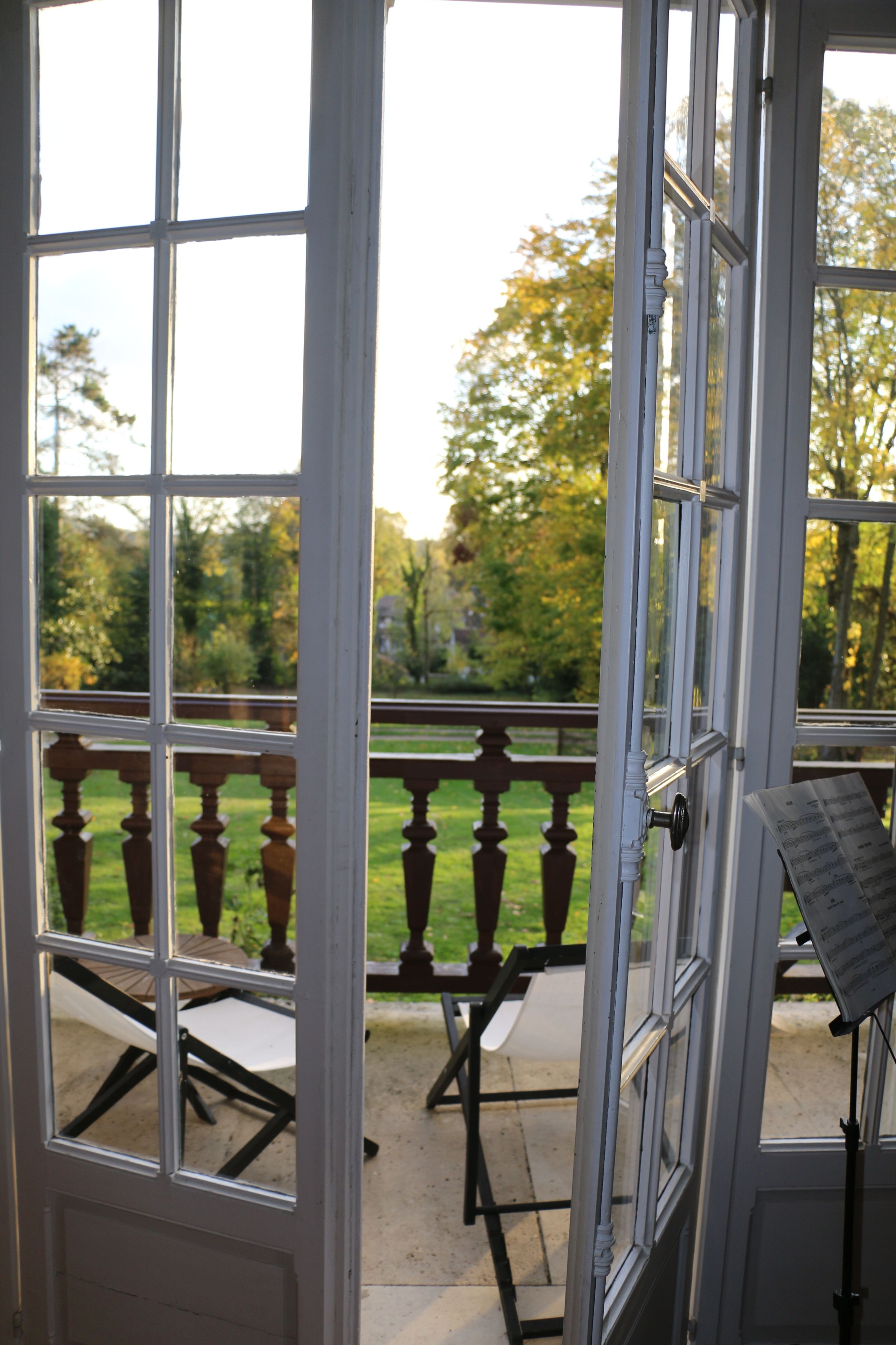 Vista desde una habitación con un ventanal grande, una terraza de madera y un piano.