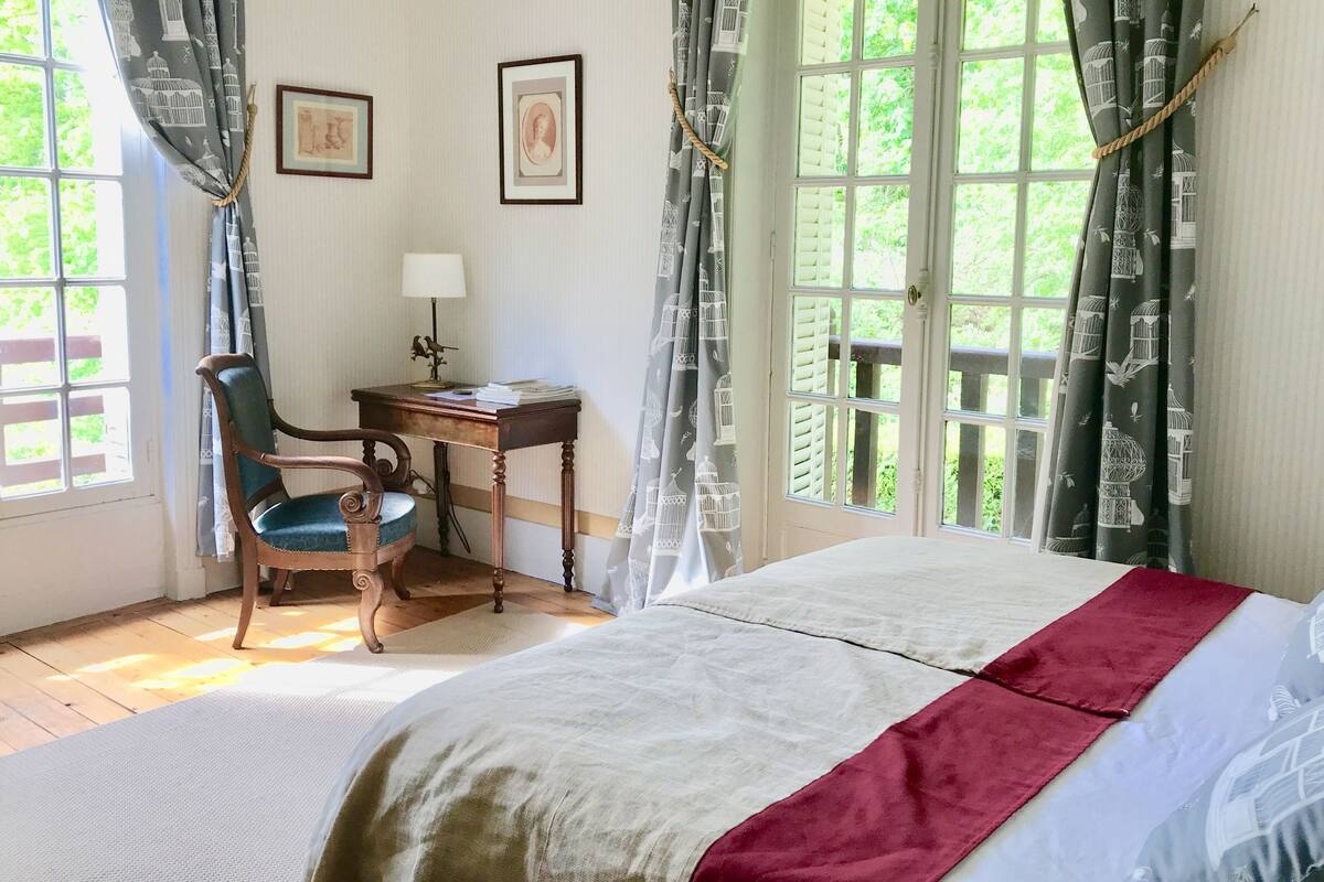 Un dormitorio con cama, escritorio, silla y dos cuadros en la pared.