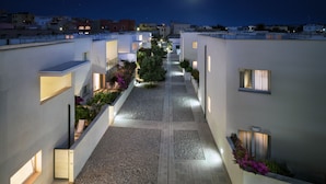 Un pasillo moderno de hotel con un camino central, pequeñas ventanas y plantas de exterior.