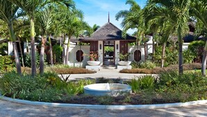 Un gazebo circondato da palme e un giardino con un elemento d'acqua.