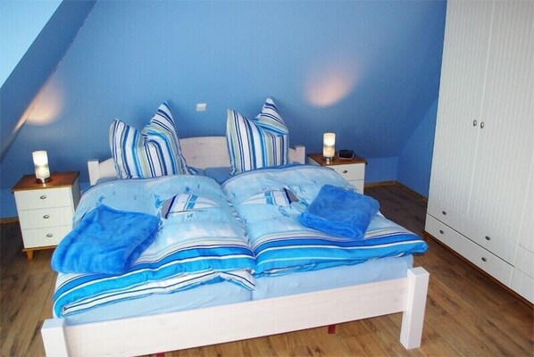 A bedroom with a white bed, blue walls, striped pillows, and bedside lamps.