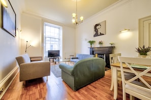 Cozy living space with a comfortable sofa, armchairs, dining table, and fireplace.
