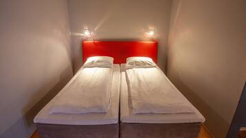 A twin room with two single beds, a red headboard, and a wooden floor.