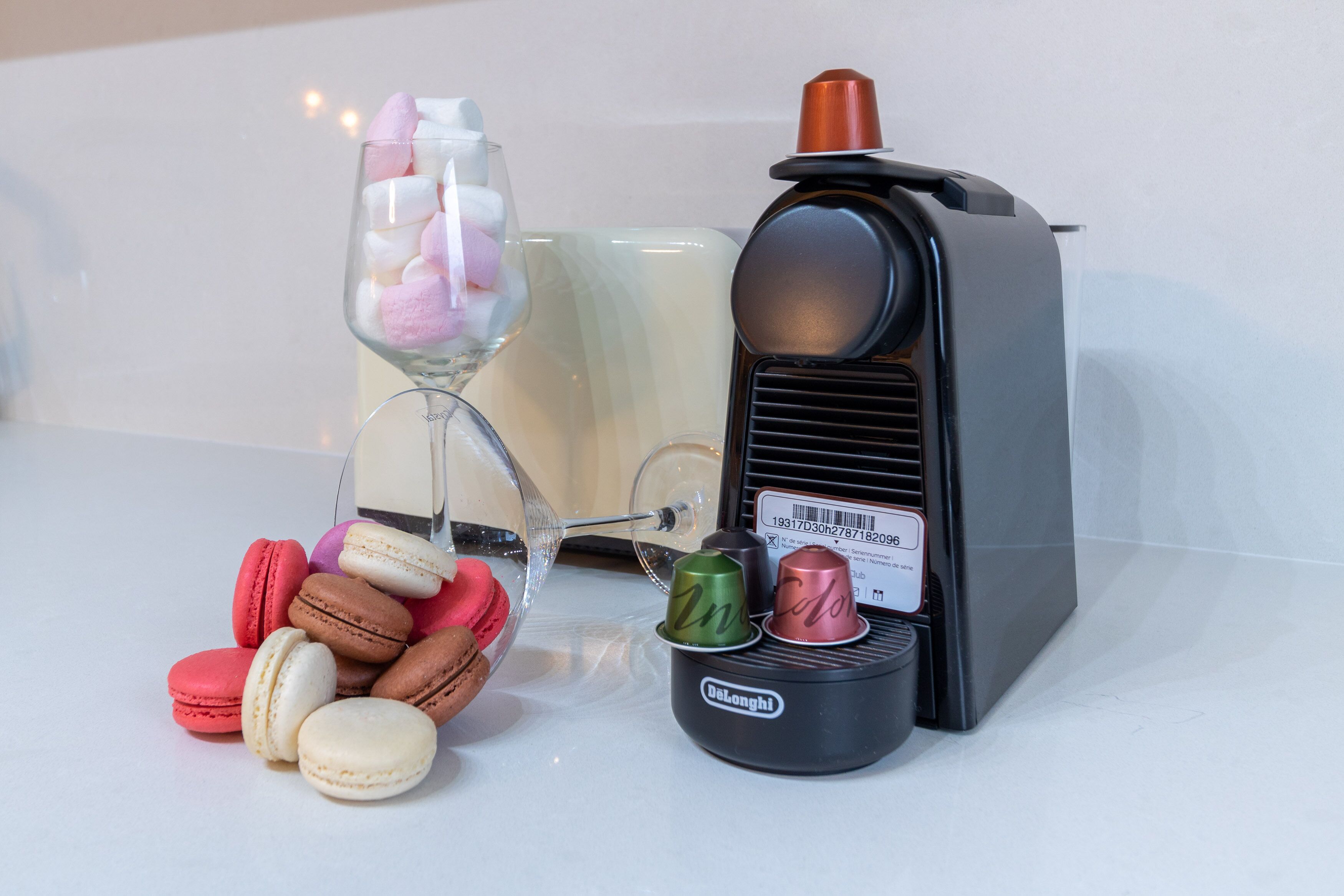 A vintage radio, a glass with marshmallows, and macarons on a white surface.