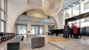 A spacious lobby with a high ceiling, a large chandelier, and a seating area with sofas and a bench. - Kook 7 Apartment - Isrentals (Jerusalem)