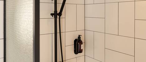 Une douche moderne dotée d’un pommeau de douche à main et d’un panneau de commande fixé au mur.
