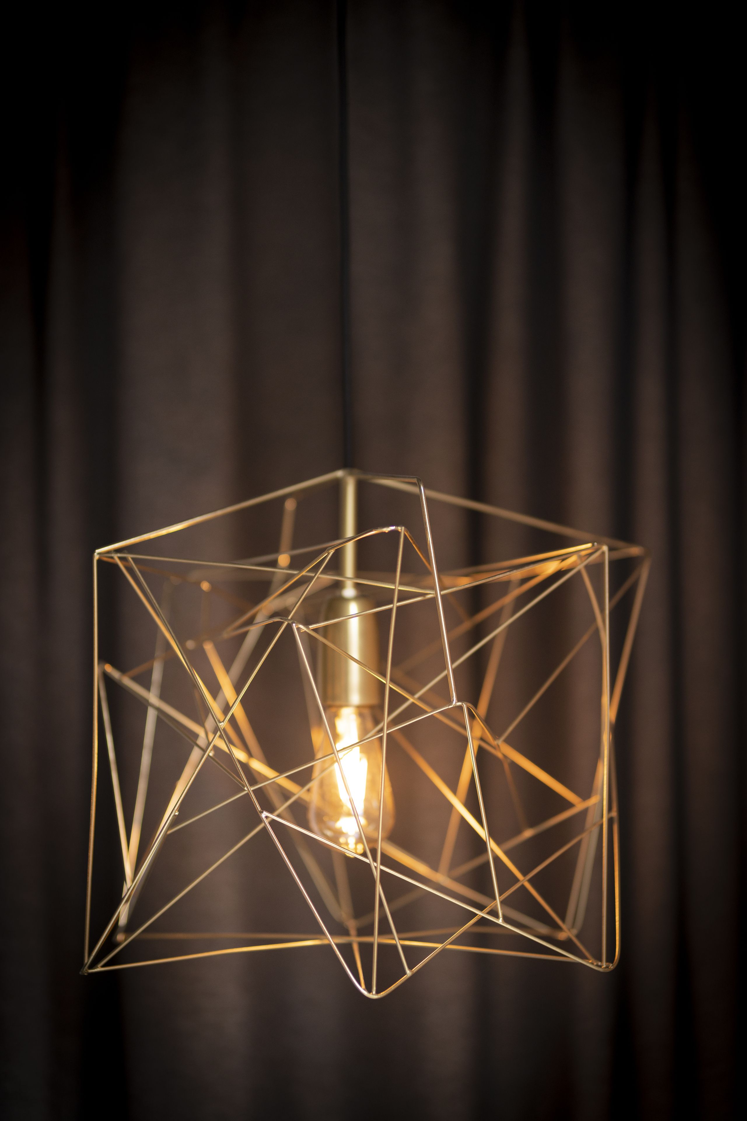 Een geometrische hanglamp met een zichtbare gloeilamp.