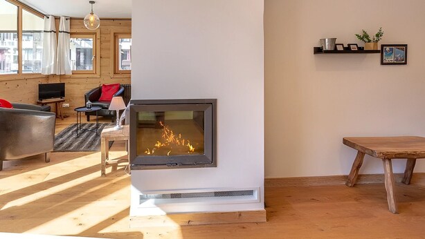 Un salón moderno con chimenea, suelo de madera y vistas a la ciudad a través de amplios ventanales.