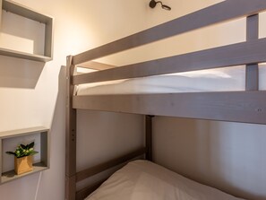 Un lit superposé avec une étagère au-dessus, sur laquelle est posée une petite plante.