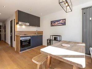 Une cuisine moderne avec des meubles de couleur sombre, un plan de travail en bois et un four encastré.