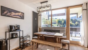 Un comedor con mesa de madera, banco y vistas a un paisaje montañoso a través de grandes ventanales.