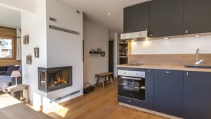 Una cocina moderna con armarios oscuros, horno integrado y chimenea.