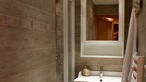 Un baño moderno con cabina de ducha de vidrio, un lavabo con espejo y un perchero para toallas.