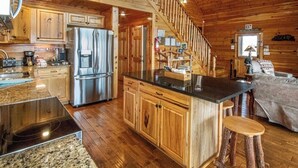L’intérieur d’un chalet en bois comprend une cuisine, un coin repas et un escalier.