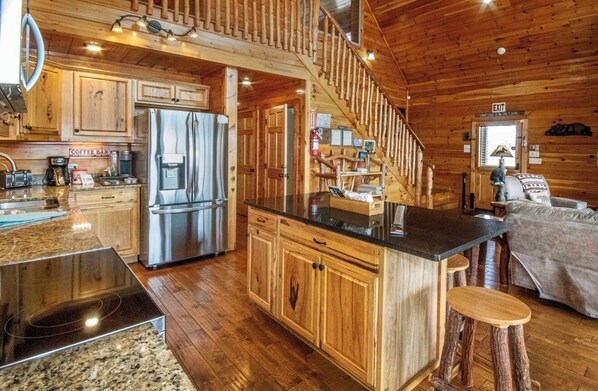 L’intérieur d’un chalet en bois comprend une cuisine, un coin repas et un escalier.