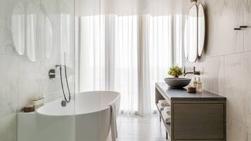Ein modernes Badezimmer mit einer freistehenden Badewanne, einem Waschtisch mit einer Schale und einem großen Spiegel.