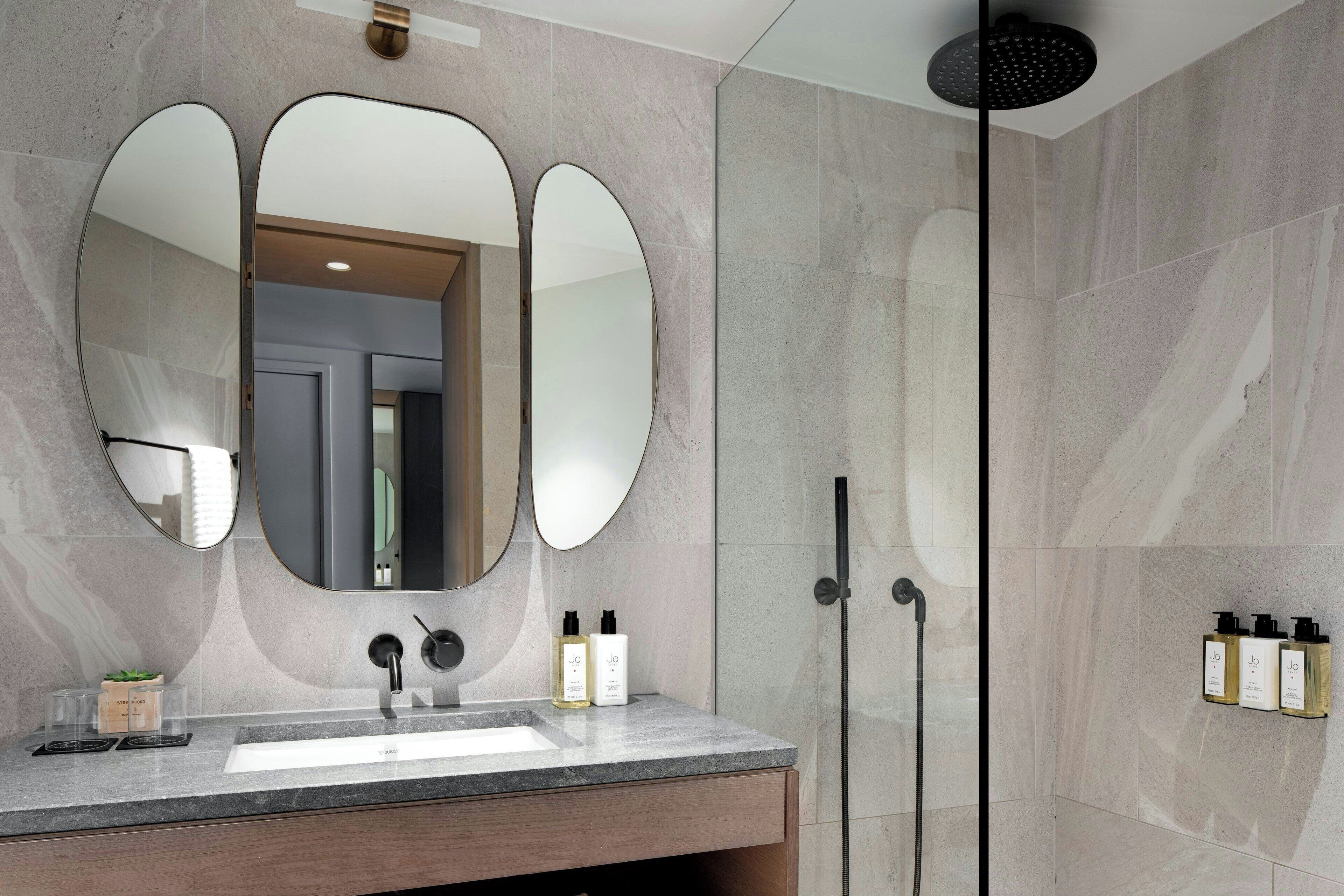 A modern bathroom with a large mirror, a sink, and a shower.