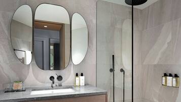 A modern bathroom with a large mirror, a sink, and a shower.
