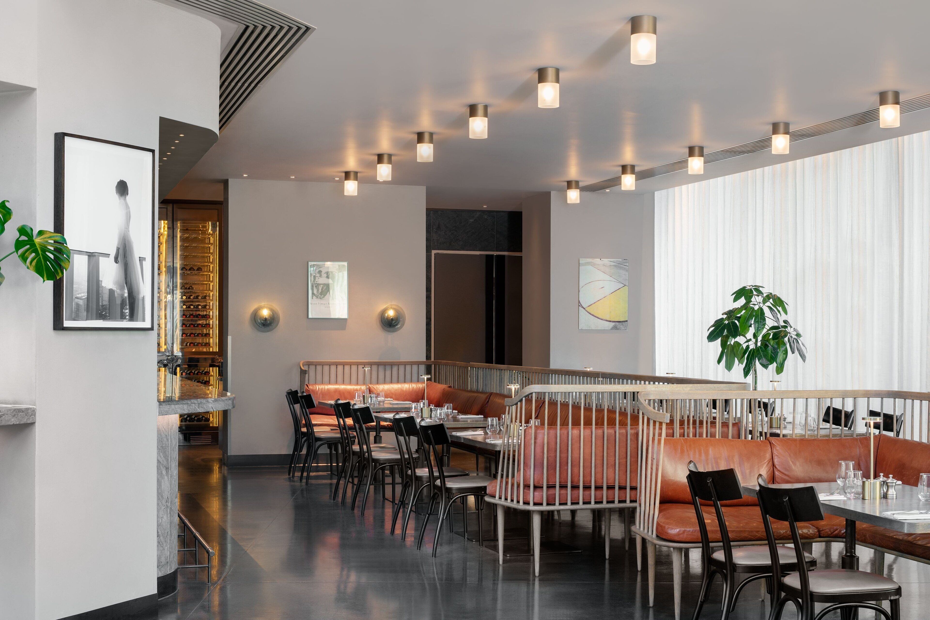 Een modern restaurant met hoge tafels en zitbanken, sfeerverlichting en decoratieve muurkunst.