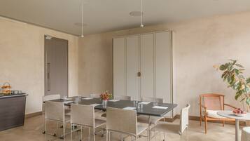 A modern dining area with a long table, multiple chairs, and a small side table with a plant.