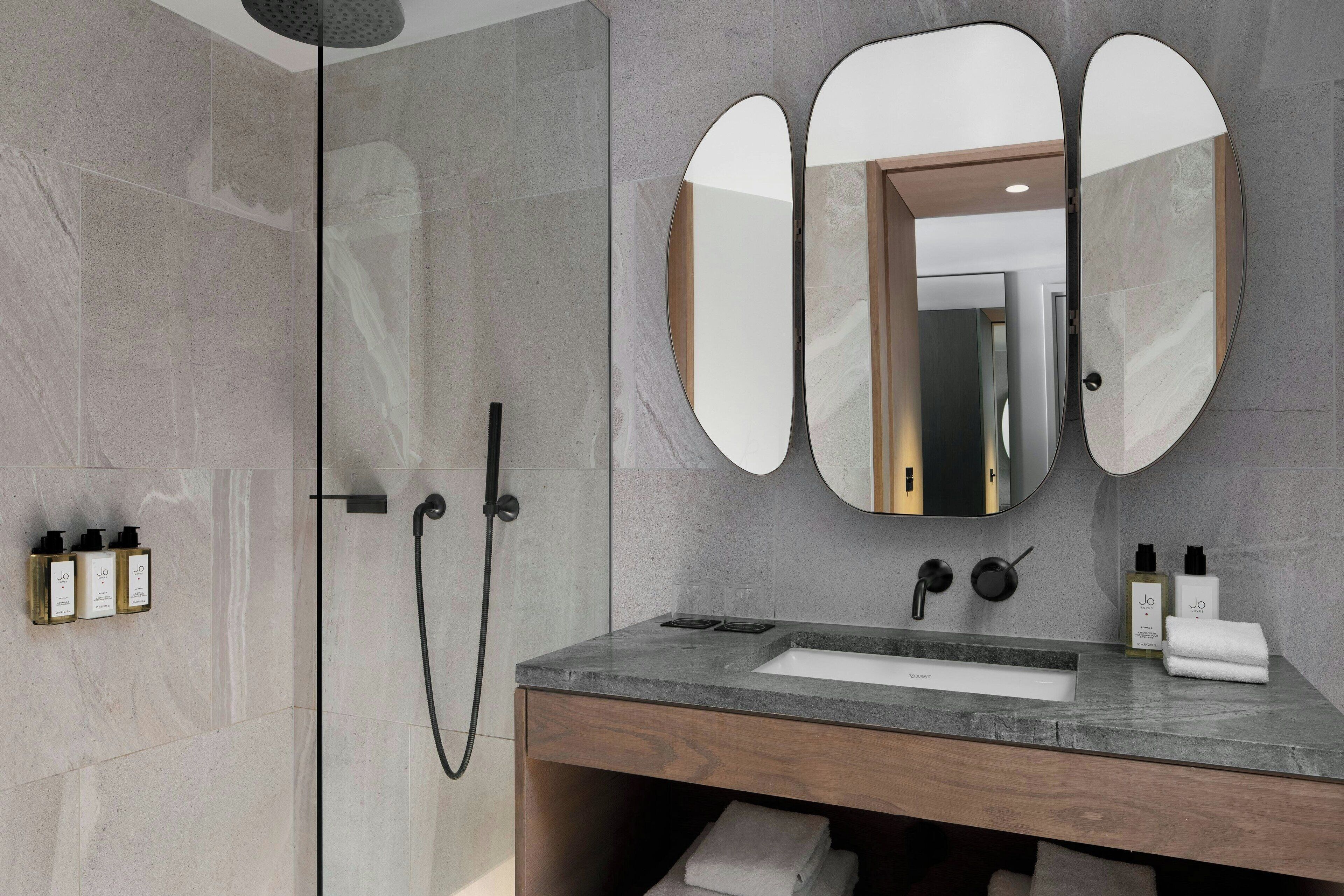 Un baño moderno con ducha, tocador y un espejo grande.