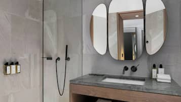 Un baño moderno con ducha, tocador y un espejo grande.