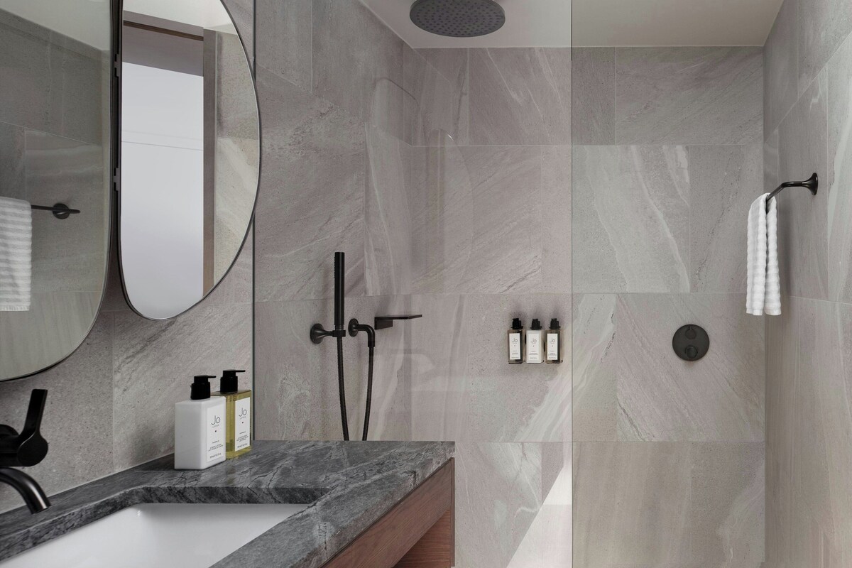 Un baño moderno con un espejo grande, una ducha y un lavabo.