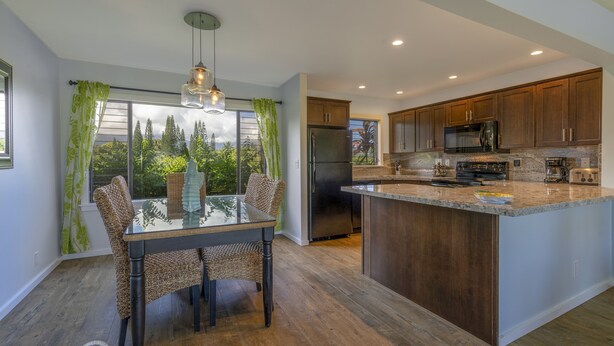 A modern kitchen with wooden cabinets, a stainless steel refrigerator, and a large island. - Beautiful views of the mountains and oceans on the ground floor (Princeville)