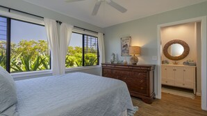A bedroom with a bed, a dresser, a ceiling fan, a window with curtains, and a view of greenery outside. - Beautiful views of the mountains and oceans on the ground floor (Princeville)