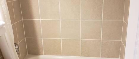 A bathroom with a bathtub, toilet, and a trash bin.