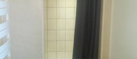 A bathroom with a shower, a toilet, and a sink with toiletries.