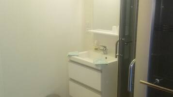 A bathroom with a sink, mirror, and a trash bin.