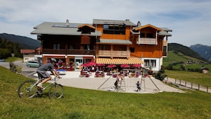 A multi-story building with a balcony, outdoor seating area, and a paved entrance. - Hôtel les skieurs (Bellevaux)